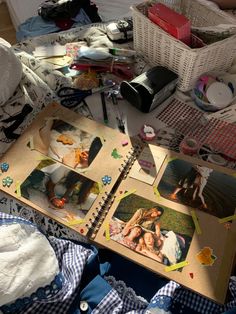 an open book with pictures on it sitting on a bed next to clothes and other items