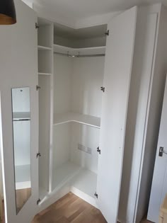 an empty closet with white walls and wooden floors