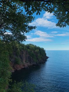 the water is calm and blue with some clouds in the sky above it, as seen from an overlook point