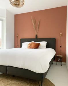 a bedroom with an orange accent wall and white bed