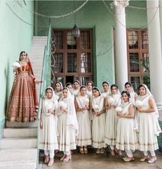 a group of women standing next to each other in front of a green building with white pillars