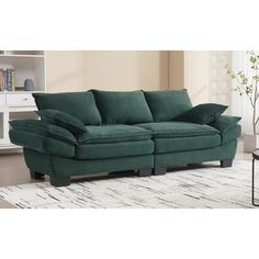 a green couch sitting on top of a rug in front of a white table and bookshelf