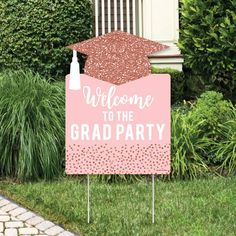 a welcome to the grad party sign with a graduation cap on it in front of some bushes