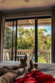 a person laying on a bed in front of a sliding glass door that leads to a deck