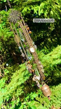 a wind chime hanging from the side of a tree in front of some trees