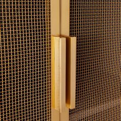 a close up view of a door handle on a wall with metal mesh behind it