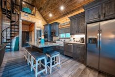 a kitchen with stainless steel appliances and wooden walls, along with stairs leading up to the second floor