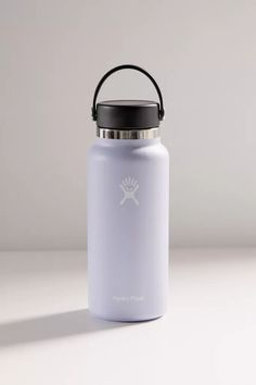 a white water bottle with a black lid on a plain surface, in front of a gray background