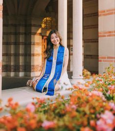 a woman sitting on the ground in front of flowers