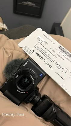 a camera sitting on top of a bed next to a receipt