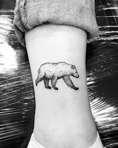 a black and white photo of a bear tattoo on the side of a woman's leg