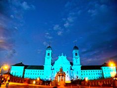 a large white building with two towers and lights on it's sides at night