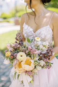 a woman in a wedding dress holding a bridal bouquet with white and yellow flowers