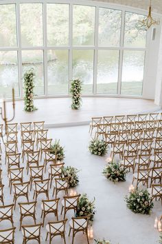 an indoor wedding venue with rows of chairs and floral centerpieces on the floor