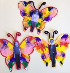 three colorful butterfly shaped magnets on a white surface with a child's face in the middle