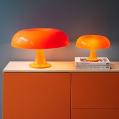 two orange lamps sitting on top of a dresser