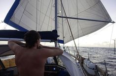 a man sitting on the back of a sailboat