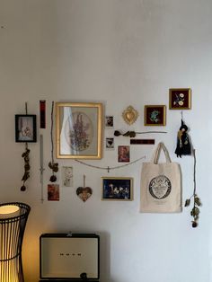 a white wall with many pictures hanging on it and a lamp next to the table