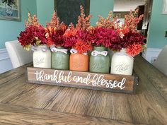 a wooden sign that says thank you all and has flowers in mason jars on it