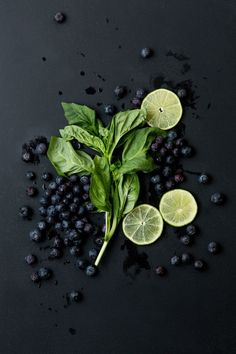 blueberries, limes and mint on a black surface