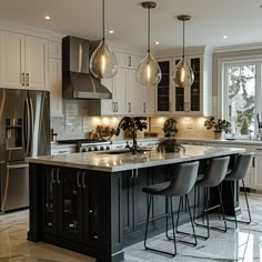 a kitchen with an island and three chairs in front of the counter top, lights hanging from the ceiling