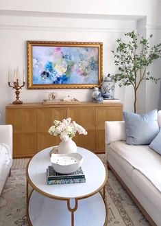 a living room filled with furniture and a painting on the wall above it's coffee table