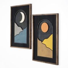 two framed art pieces with mountains and moon in them on a white wall next to each other