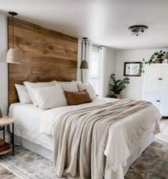 a bedroom with white bedding and wooden headboard