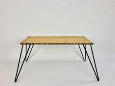 a wicker table with black legs on a white background