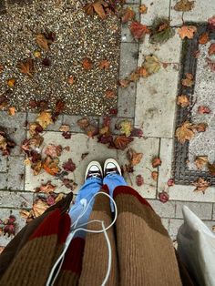 a person standing on top of a sidewalk next to leaves