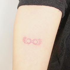 a small pink tattoo on the arm of a woman's left arm, with an outline of two glasses