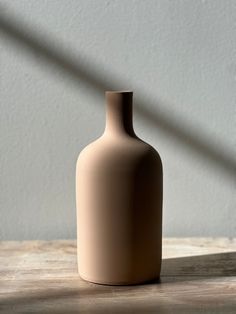 a beige vase sitting on top of a wooden table