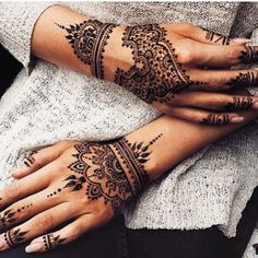 two hands with henna tattoos on them