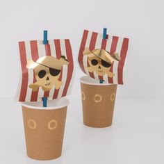 two paper cups with straws decorated to look like pirates