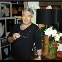 a man standing in front of a table with flowers and pictures on the wall behind him