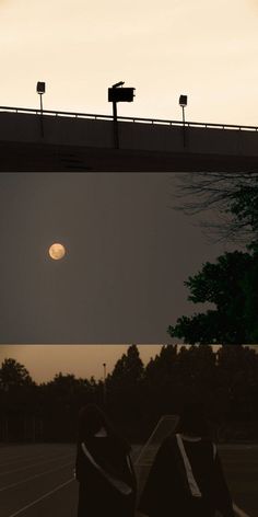 two people are sitting on the bench watching the sun go down in the sky above them