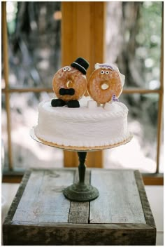 two donuts sitting on top of a frosted cake with faces drawn on them