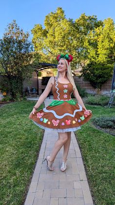 a woman in a dress that is standing on a brick walkway with her hands behind her back