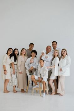 a group of people standing next to each other in front of a white wall and chair