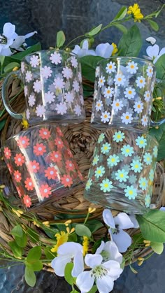 four glass mugs sitting on top of a basket filled with flowers