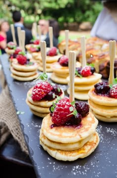 pancakes with raspberries and strawberries on them are lined up on a table