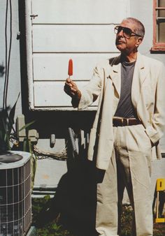 an older man is holding something in one hand and standing next to a truck with it's door open