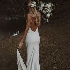 a woman in a white dress holding a bouquet of flowers and wearing a flower crown