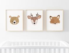 three animal prints hanging on the wall above a crib in a white nursery room