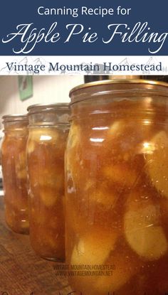 four jars filled with apples sitting on top of a wooden table