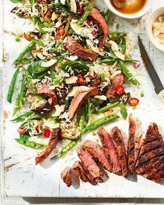 a cutting board with steak, green beans and other food items on top of it