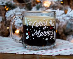 a glass mug sitting on top of a table next to a christmas tree