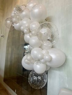 a bunch of white balloons hanging from the side of a wall next to a mirror