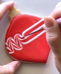 someone is decorating a heart shaped cookie with icing