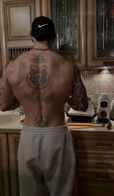 a man with tattoos on his back standing in front of a sink